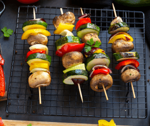 Photo of vegetable shish kababs, including mushrooms, onions, zucchini,, and bell pepper