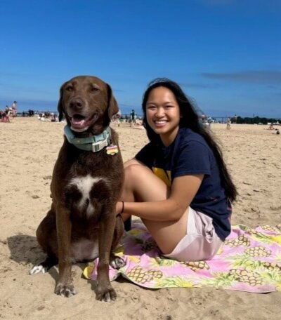 Photo of Erin Turner with her dog, a chocolate lab, at the beach.