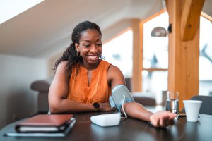 Black woman in orange shirt taking blood pressure